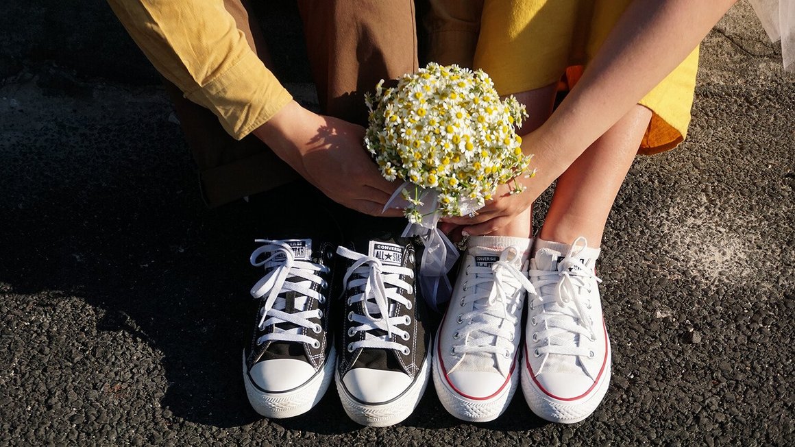 Para siedzi na ziemi z kwiatami w ręku - planowanie ślubu