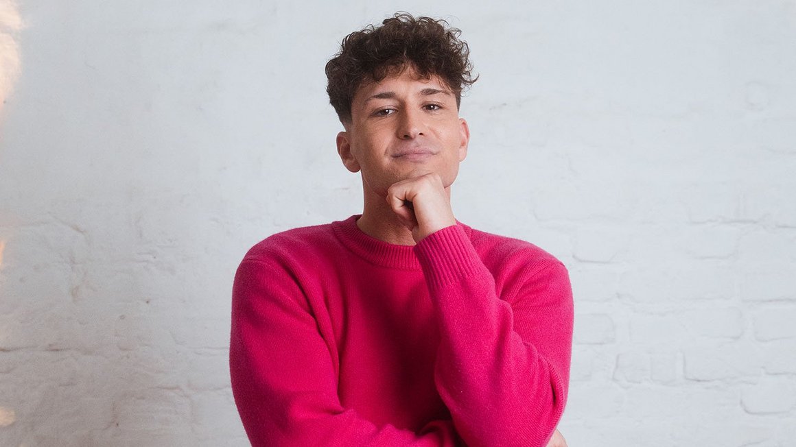 Bezpieczeństwo przede wszystkim: redukcja zadłużenia i oszczędności Mężczyzna w różowym swetrze patrzący zamyślony w kamerę