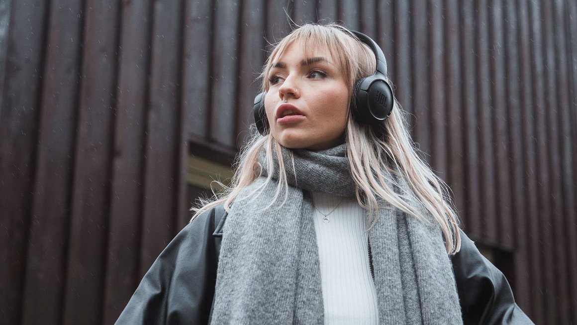 Budowanie bogactwa za niewielkie pieniądze: Od czego zacząć Młoda kobieta ze słuchawkami patrząca w dal