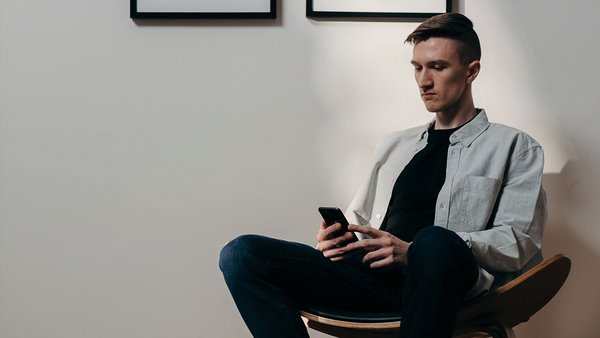 Mężczyzna patrzy niespokojnie na swój telefon komórkowy - wzrost cen Mężczyzna patrzy niespokojnie na swój telefon komórkowy - wzrost cen