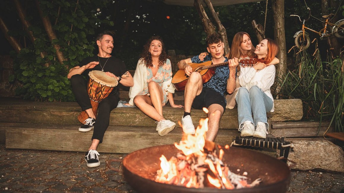 Młodzi ludzie siedzący przy ognisku - Przygoda życie w vanie