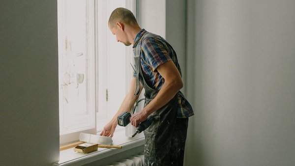 Mężczyzna naprawia okno - prywatne ubezpieczenie od niezdolności zawodowej