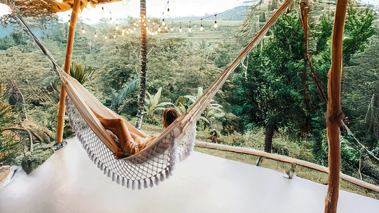 Kobieta relaksuje się na hamaku i podziwia zielony krajobraz.