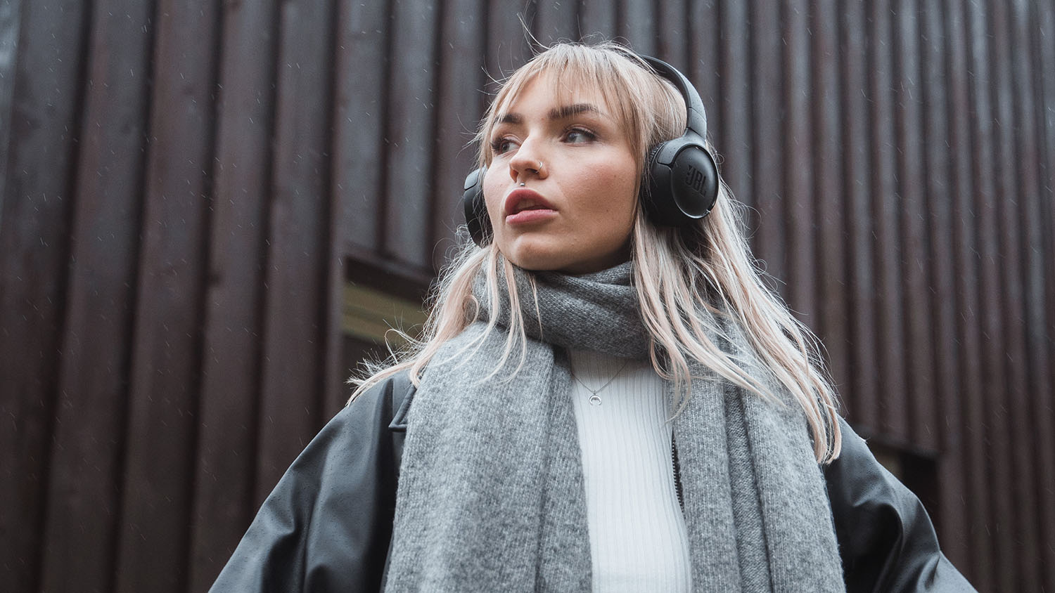 Młoda kobieta ze słuchawkami patrząca w dal