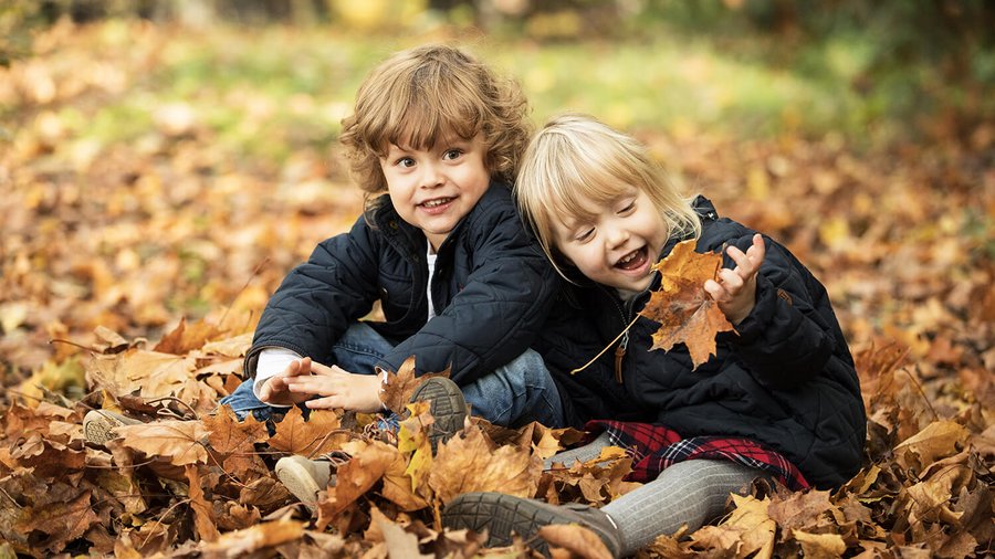 Dwójka dzieci siedząca w jesiennych liściach
