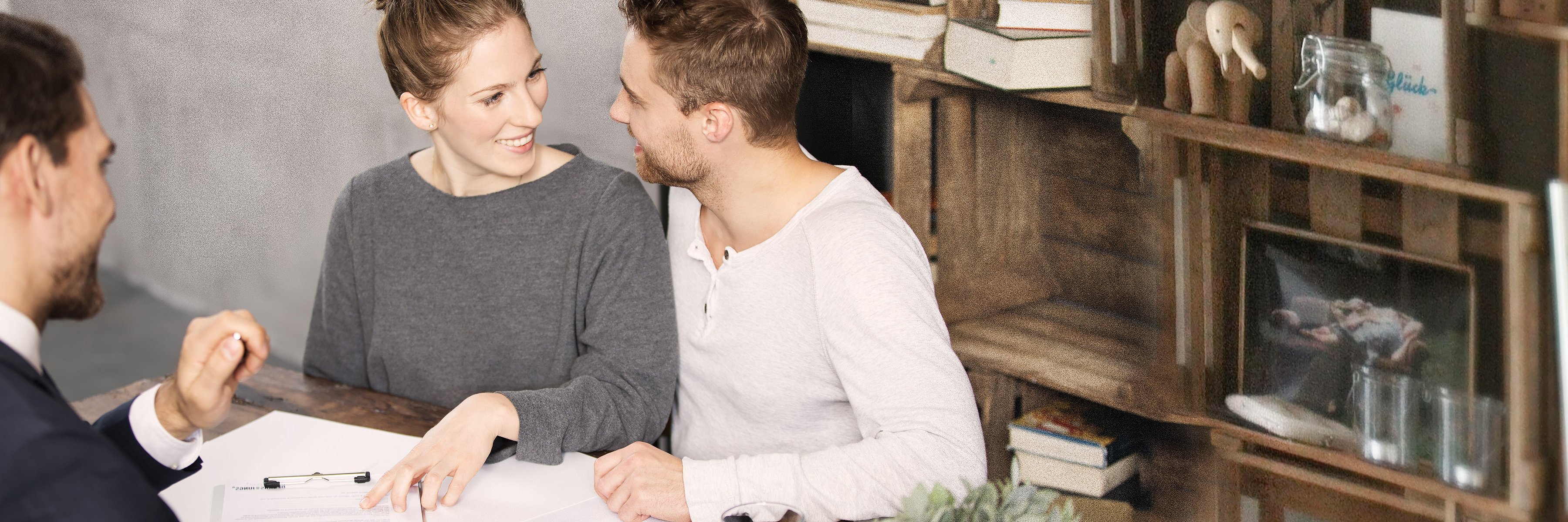 Młoda para siedzi uśmiechnięta u doradcy finansowego.