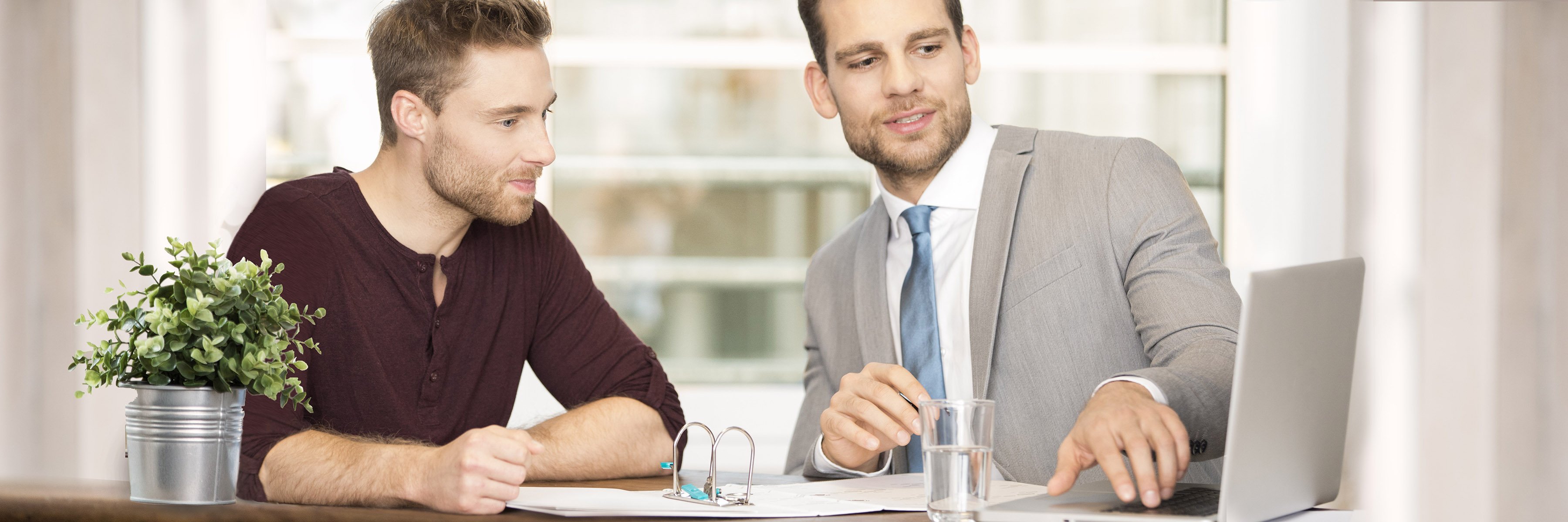 Doradca finansowy pokazuje klientowi coś na laptopie.