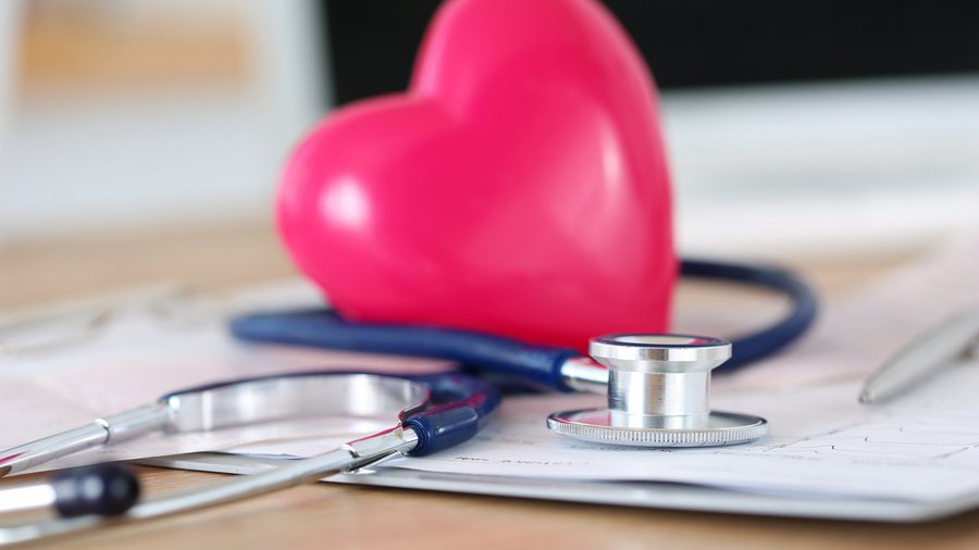 Stetoskop i stylizowane serce leżą na stole.
