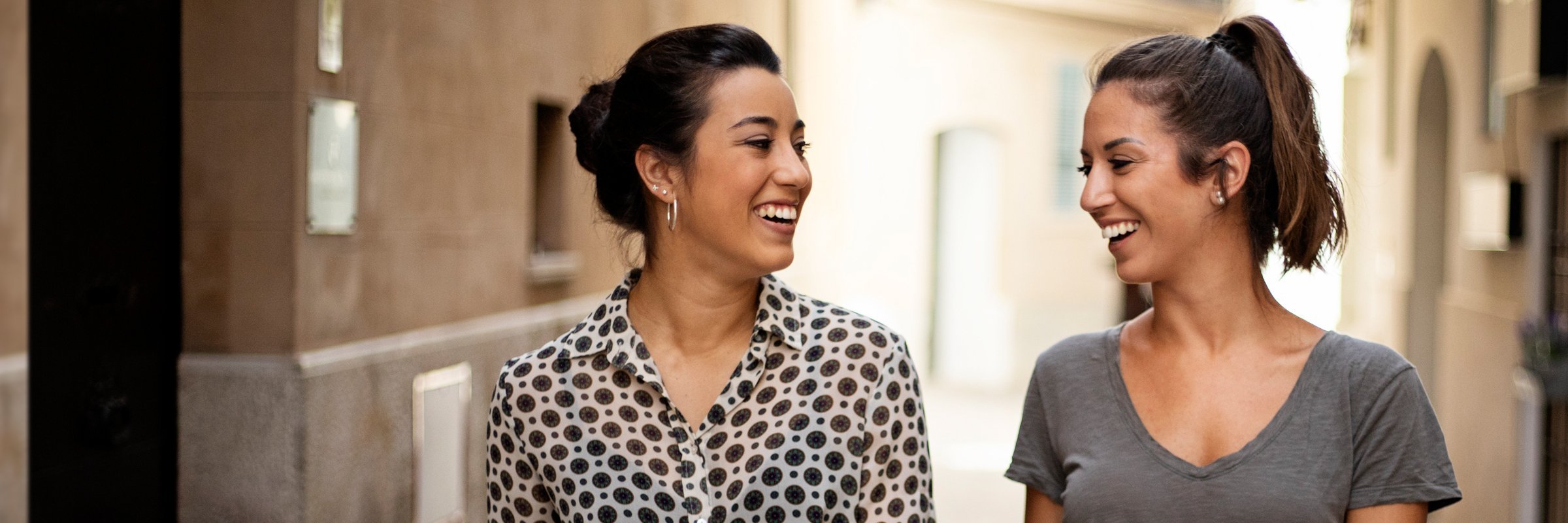 Dwie kobiety prowadzą ożywioną rozmowę na ulicy.